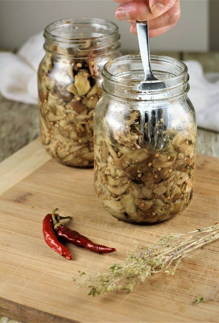 packing eggplant into mason jars with fork