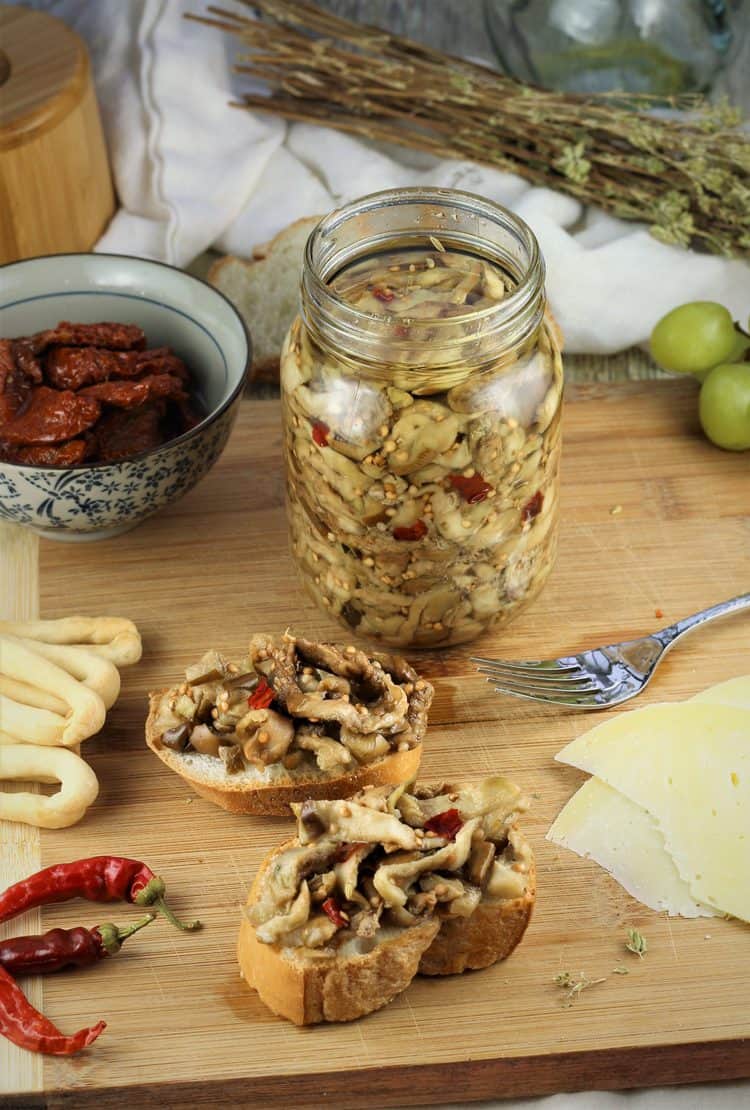 jar of pickled eggplant on wood board with antipasto