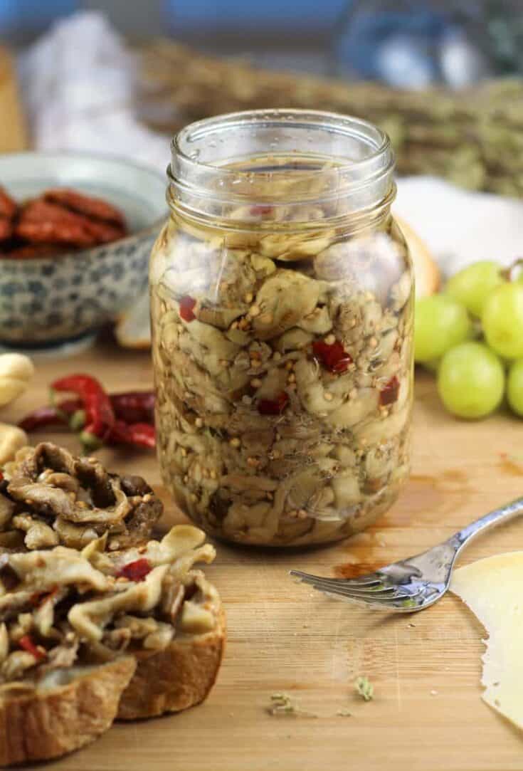 jar of pickled eggplant with fork and crostini on side