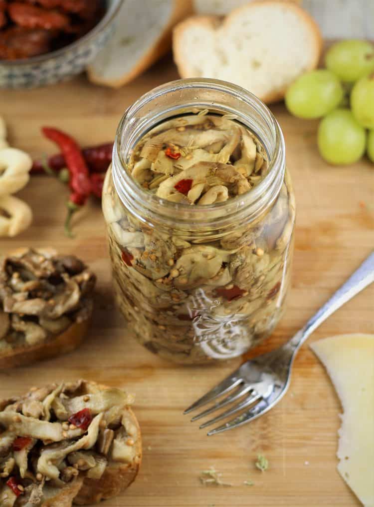 jar of pickled eggplant with fork and crostini around it