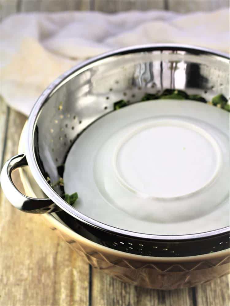 colander with hot peppers with plate weighing them down in large bowl