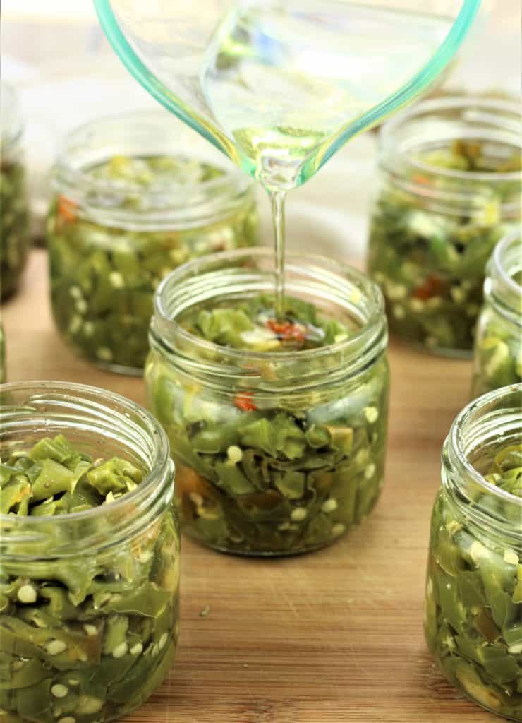 topping off jars with Italian hot pickled peppers with oil