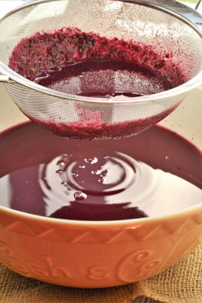straining grape must with sieve over bowl