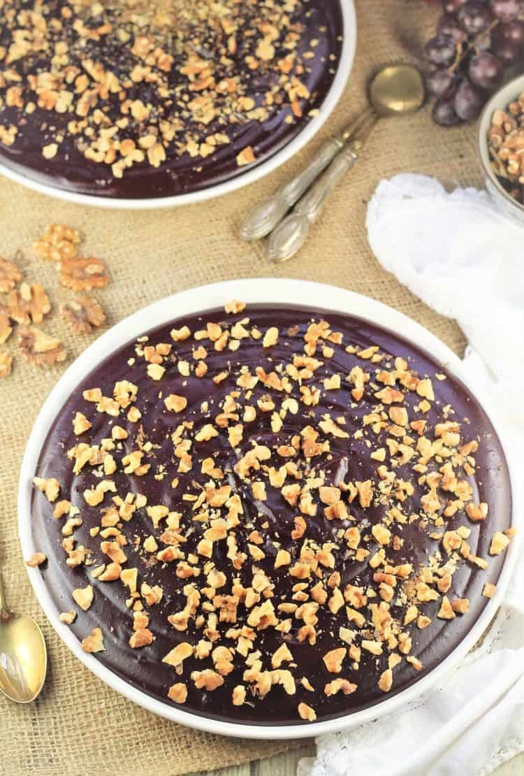 two plates filled with grape must pudding (mostarda di uva) and walnuts with serving spoons