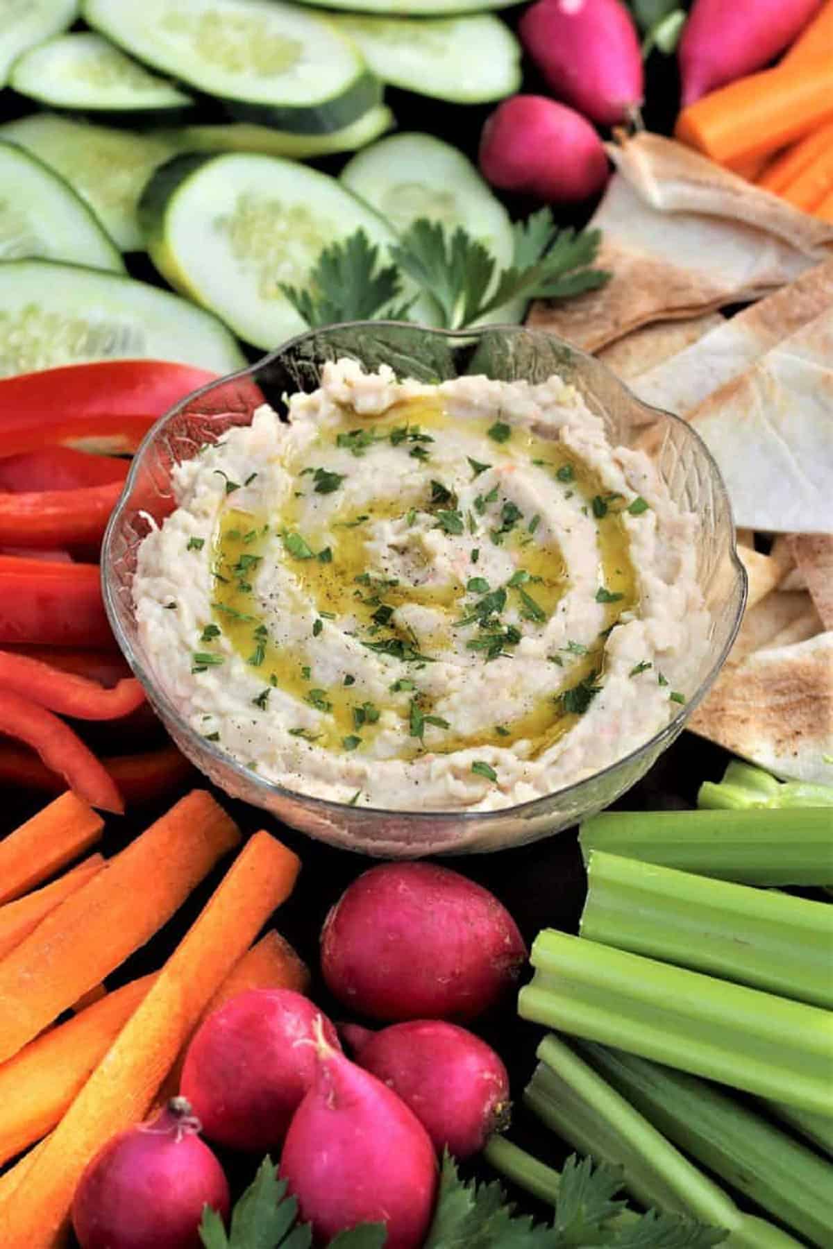 White BEan DIp White bean dip garnished with parsley surrounded by crudités.