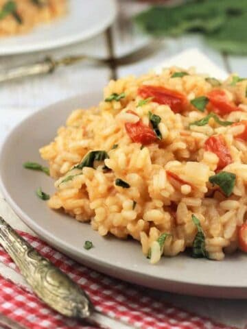 Tomato and basil risotto plated next to fork.
