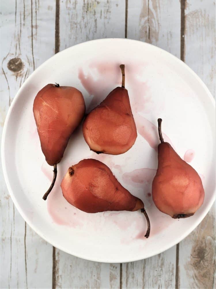 pears poached in red wine on white round plate