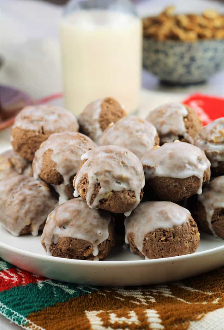 glazed chocolate cookies piled onto a plate with milk bottle in background