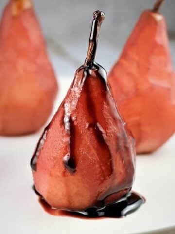 Pears poached in red wine with red wine reduction poured over them.