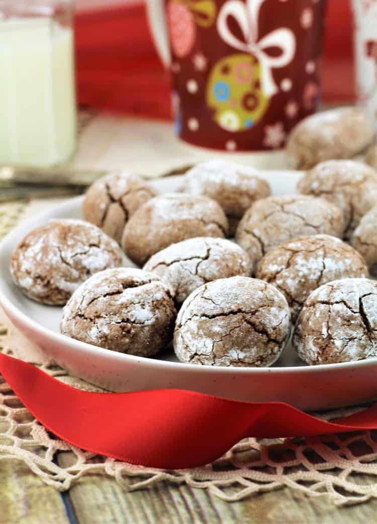 chocolate espresso amaretti on plate with red ribbon in front and mugs in background