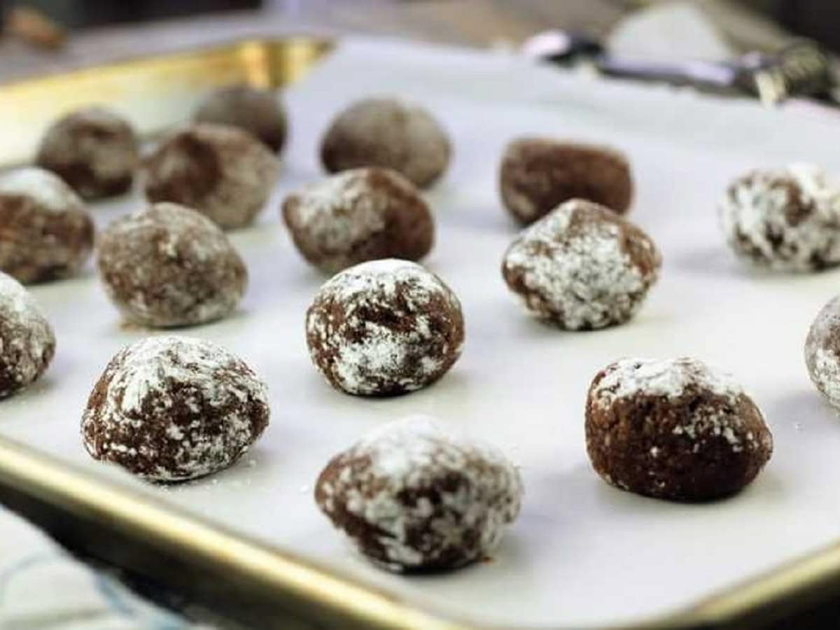 Italian almond cookies with chocolate dough balls on baking sheet.