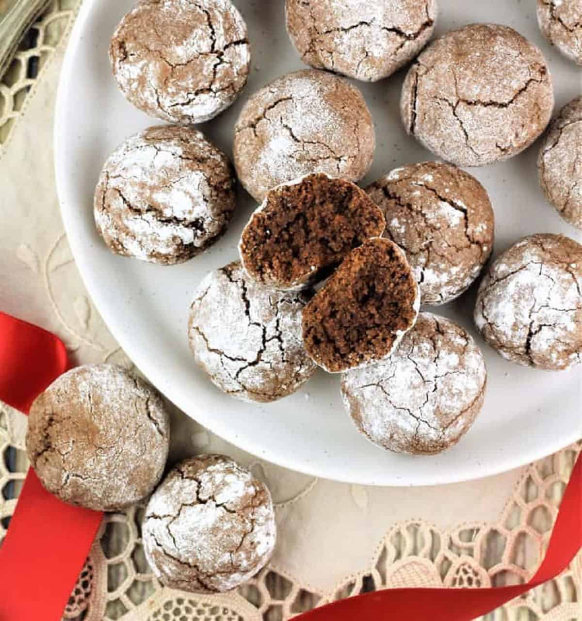 Chocolate espresso amaretti cookies on plate with one cookie cut in half.