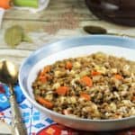 blue rimmed bowl with lentils and rice on colorful dish cloth with spoon on side