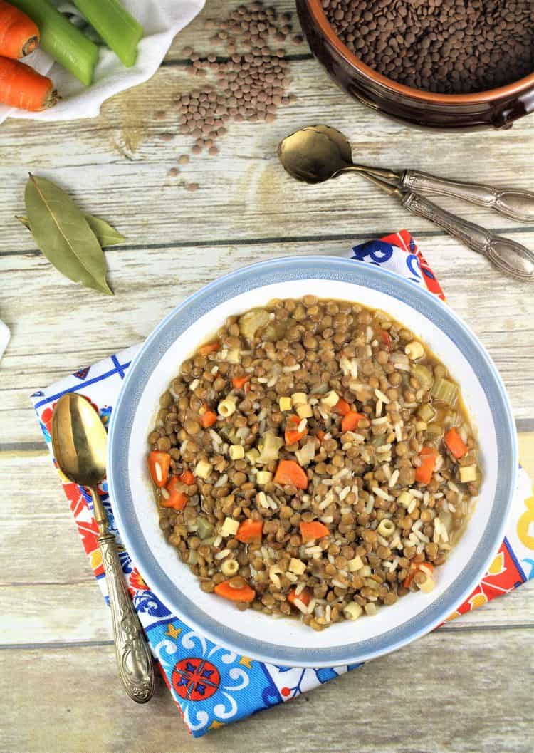 overhead view of lentils with rice in blue rimmed bowl with spoon on side