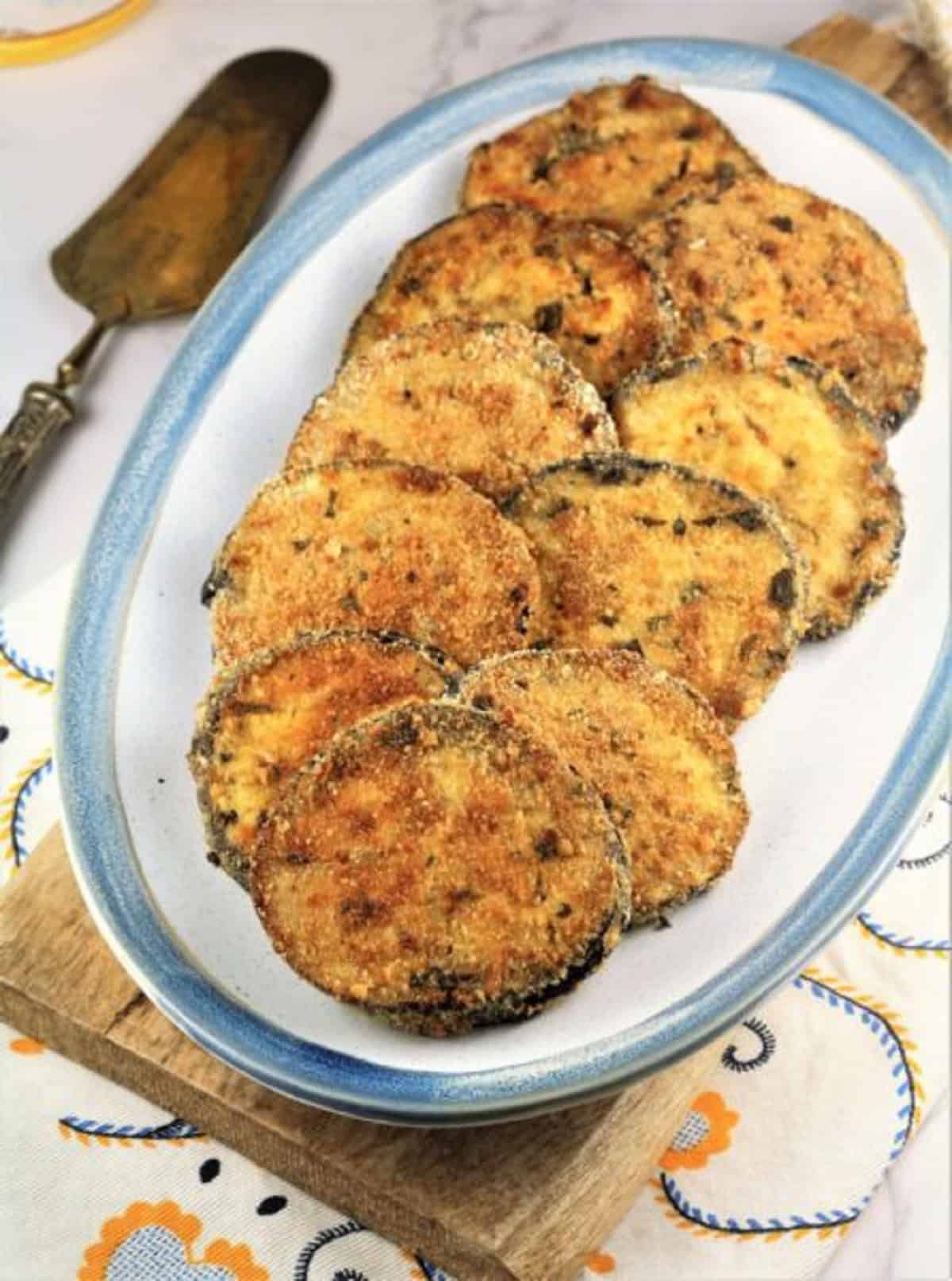 Breaded baked eggplant cutlets on oval serving plate.