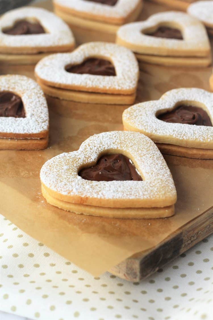Nutella filled heart cookies on parchment paper covered board