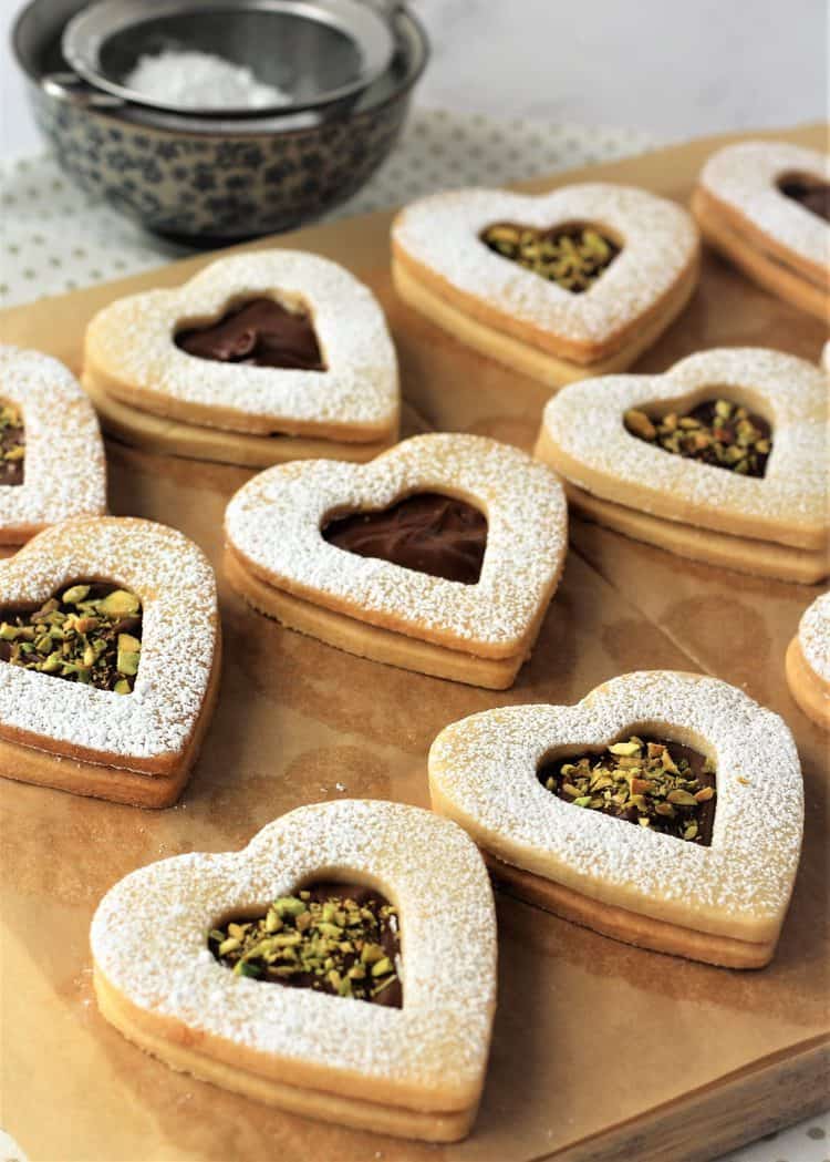 Nutella and pistachio filled heart cookies on parchment paper