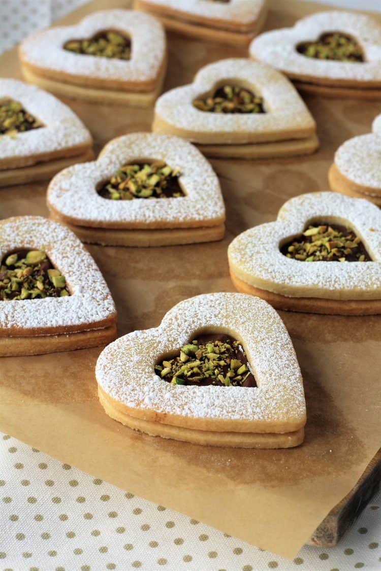 Nutella and pistachio filled heart cookies on parchment paper