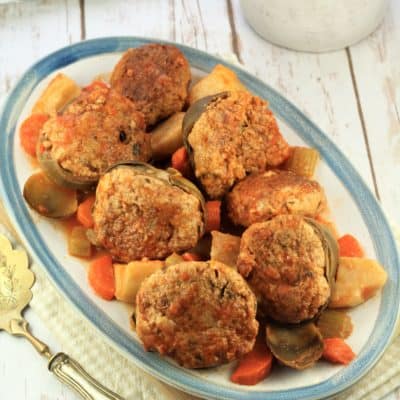 serving plate filled with stewed stuffed artichokes and vegetables