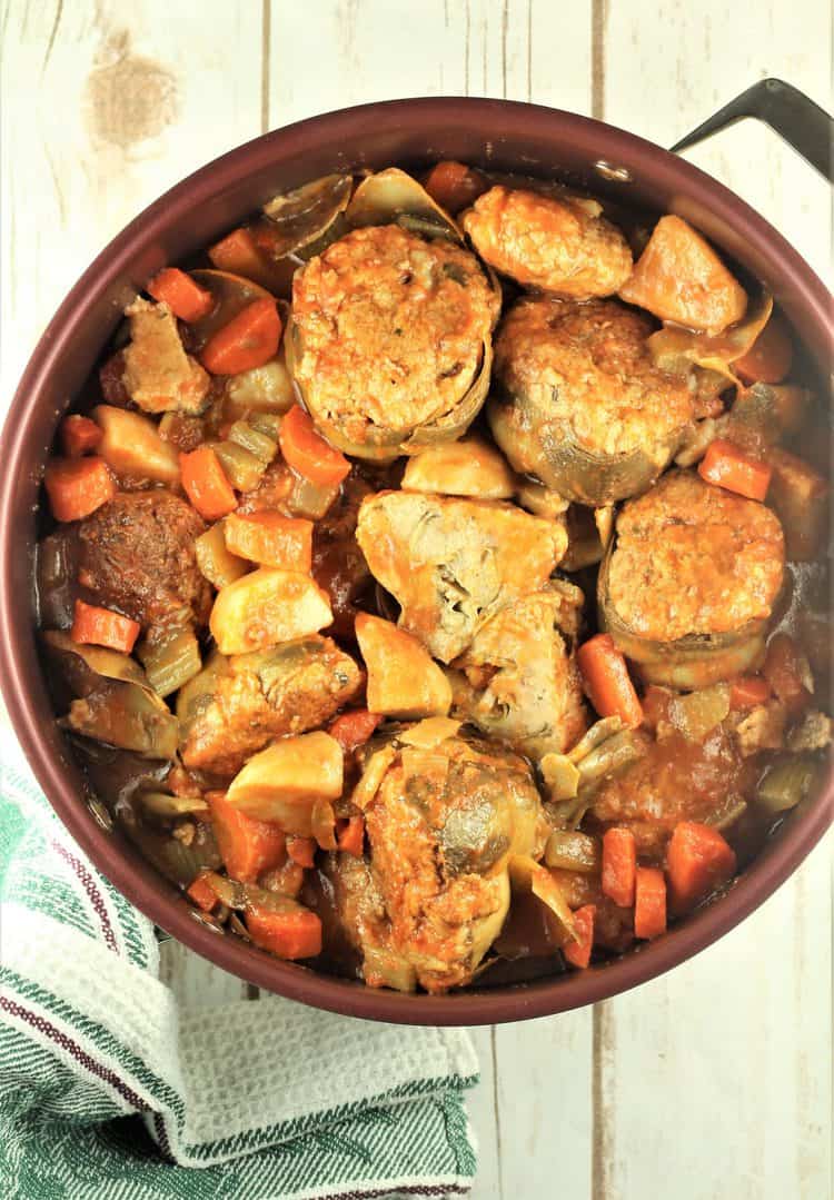 large sauce pan with stewed stuffed artichokes and vegetables