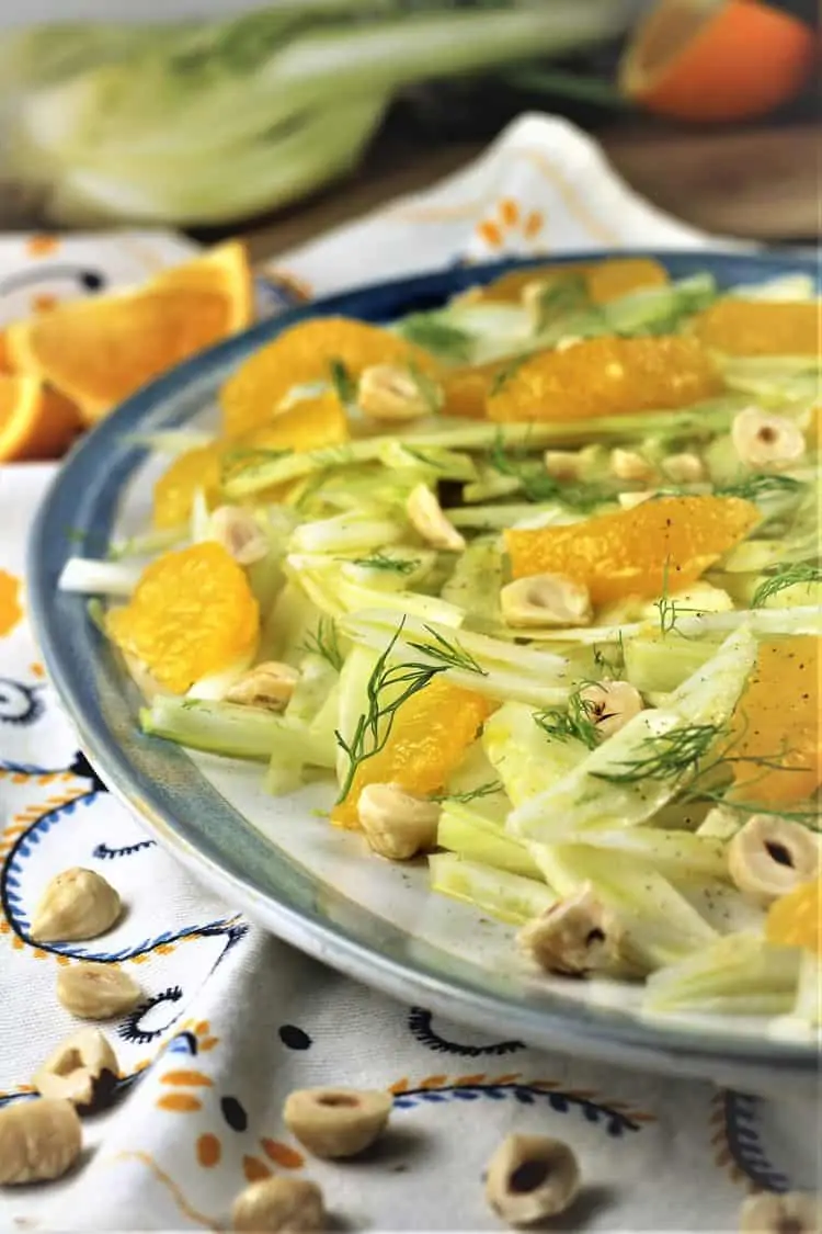 blue rimmed white platter with sliced fennel and orange segments with hazelnuts