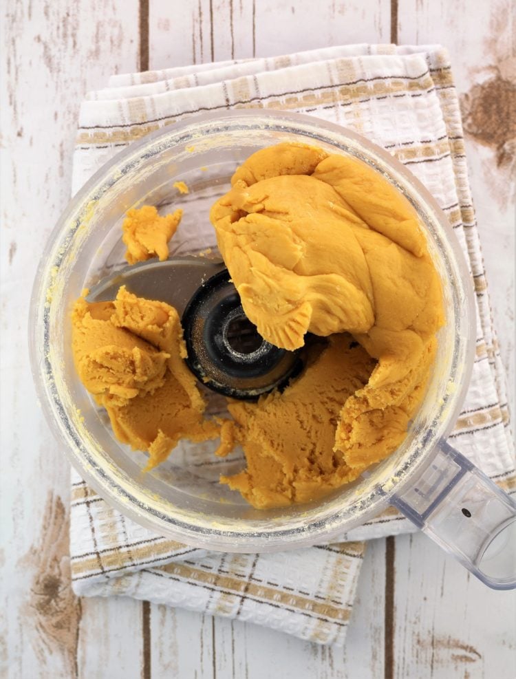 chickpea flour dough wrapped around blade in bowl of food processor