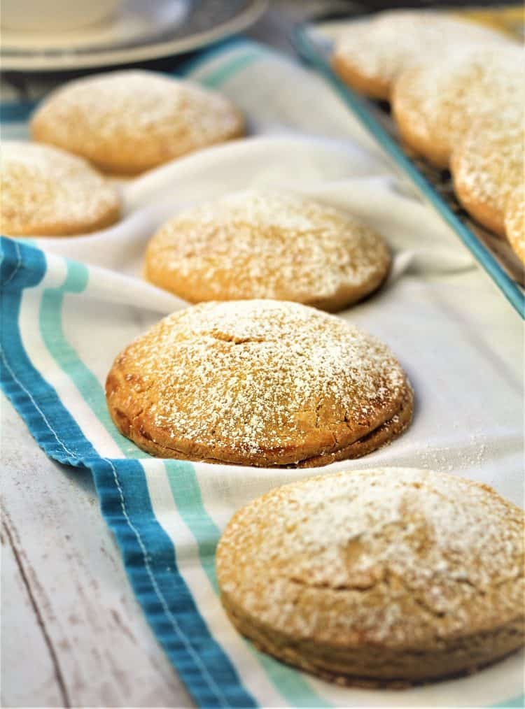 4 round sweet panelle cookies dusted with powdered sugar on dish cloth