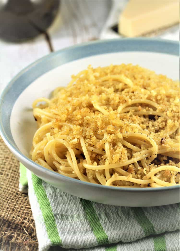 blue rimmed white bowl filled with spaghetti with breadcrumbs 