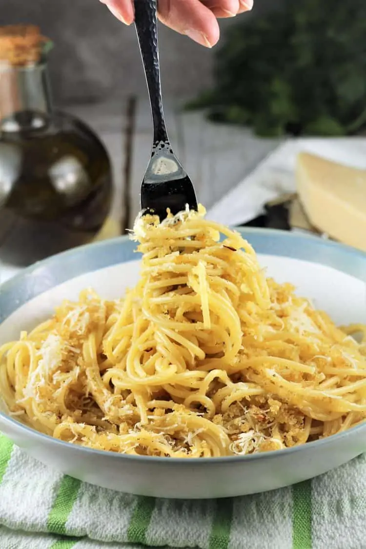 fork twirling around spaghetti with breadcrumbs in pasta bowl