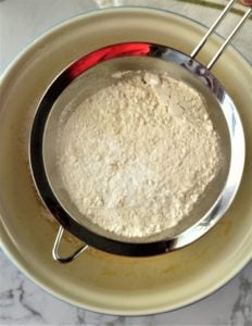 flour in sieve sifted over mixing bowl
