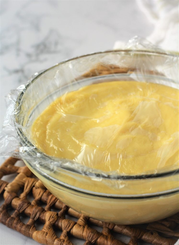 glass bowl with pastry cream with plastic wrap over the surfacce