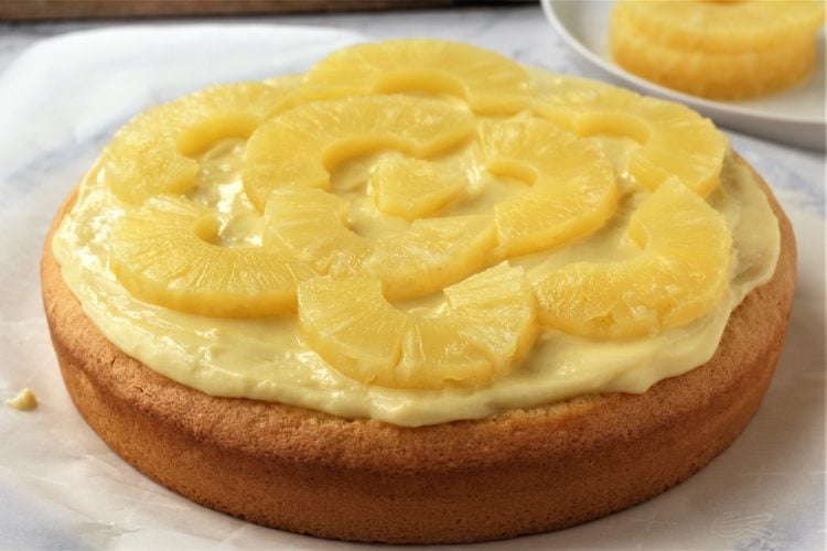 pineapple slices covering pastry cream on sponge cake