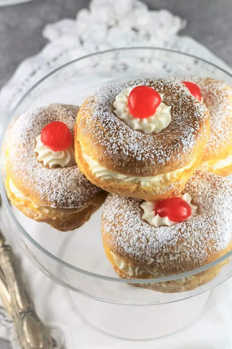 3 zeppole on glass plate with cherries on top