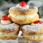 glass plate piled with zeppole with ricotta filling and cherry on top