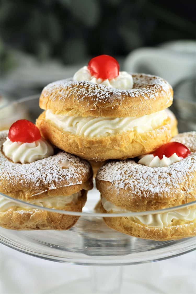 closeup of 3 zeppole with cherry on top on glass plate