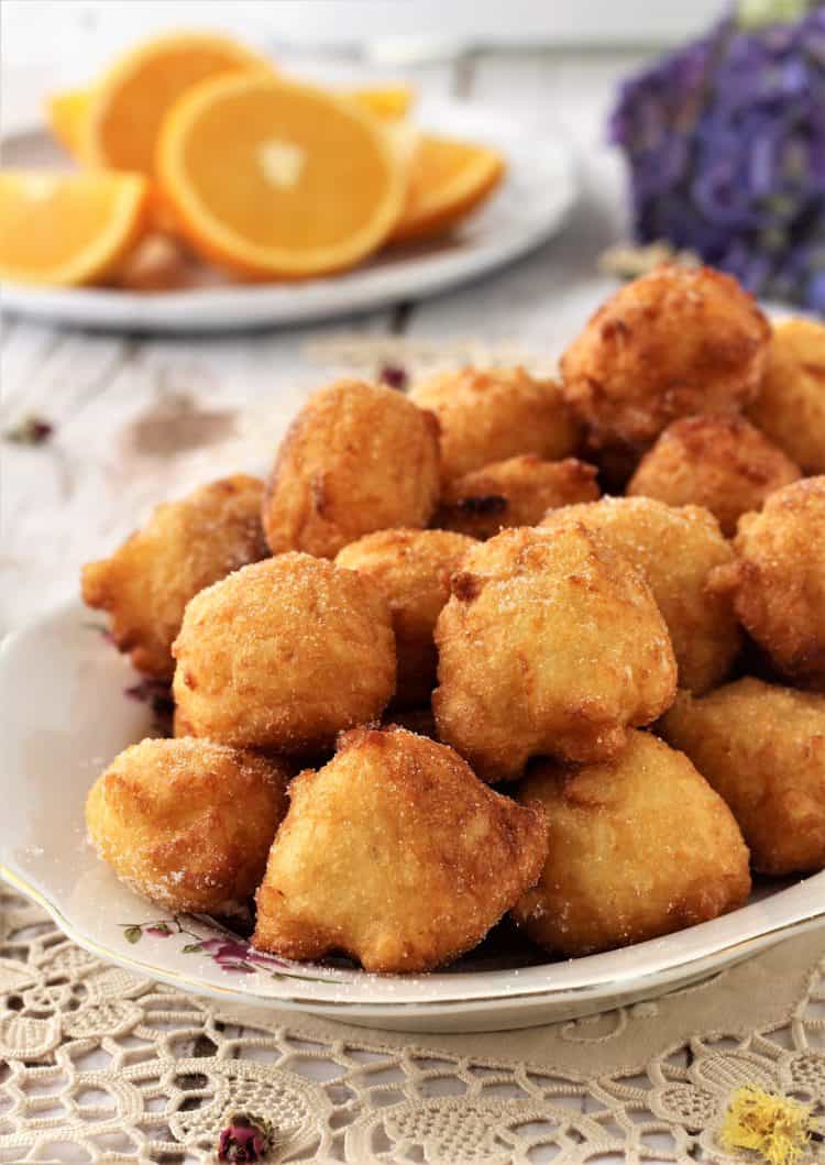 platter of sweet rice sfinci with plate or orange wedges behind it
