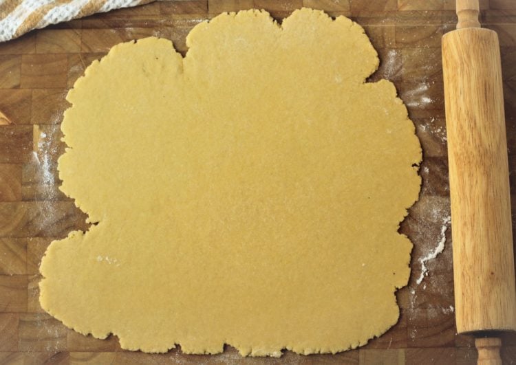 rolled pie crust on wood board with rolling pin