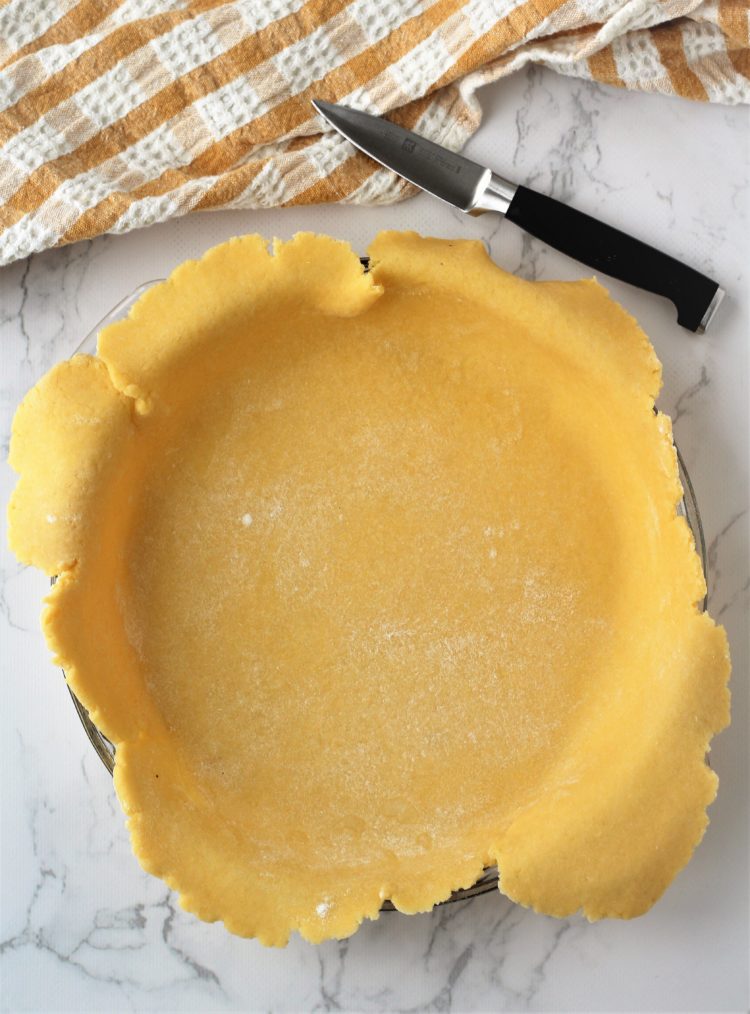 rolled pie crust with sides hanging over pie plate