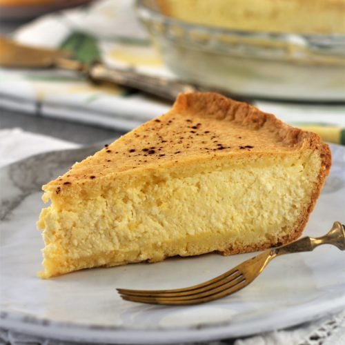 Wedge of ricotta pie on white plate with fork on side.