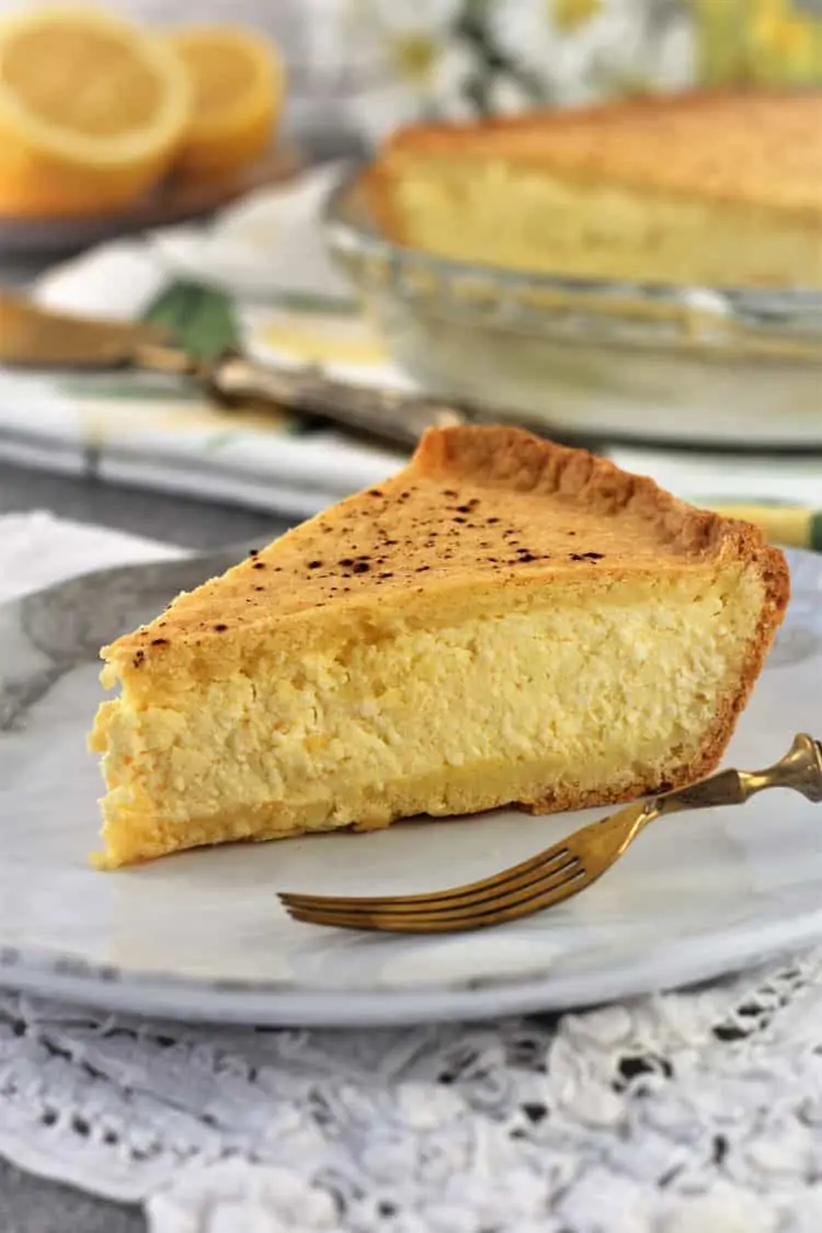 wedge of ricotta pie on white plate with fork on side