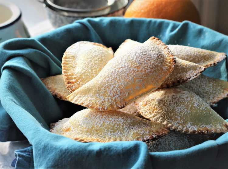 Sicilian Cassatelle with Ricotta basket lined with blue napkin filled with crescent shaped sweet dough cookies