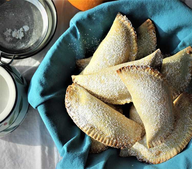 crescent shaped ricotta filled cassatelle in blue cloth covered basket