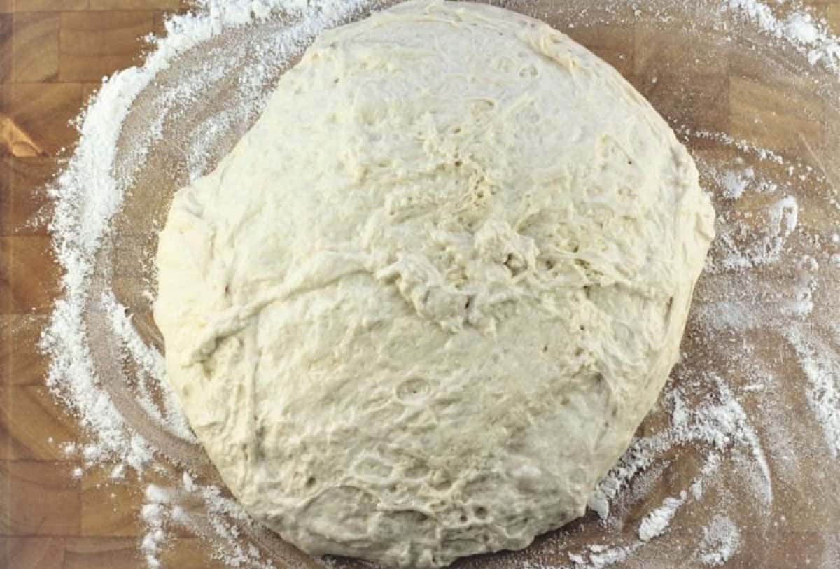 No knead pizza dough ball on wood board.