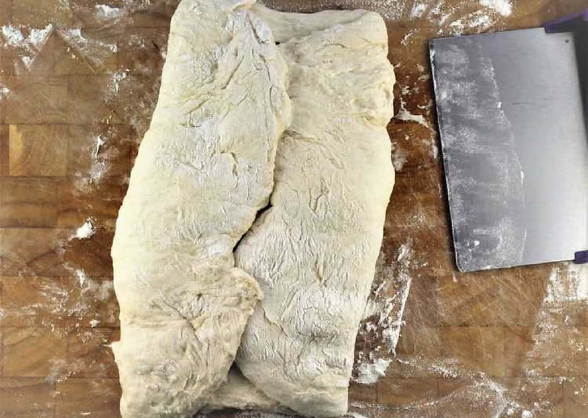 No knead bread dough folded over cheese and olive filling on wood board.