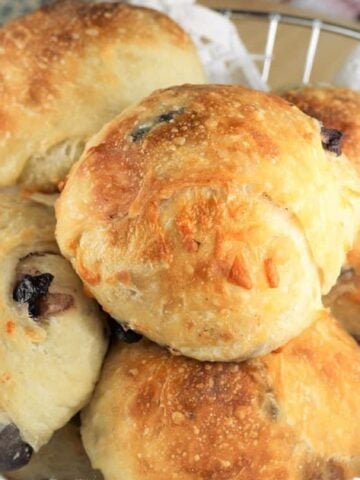 Italian olive and cheese stuffed buns piled in basket.