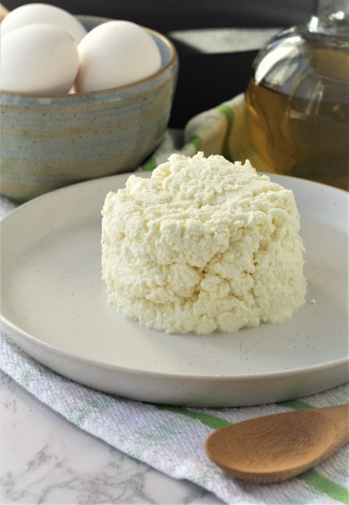 white plate with mound of ricotta and bowl of eggs in background