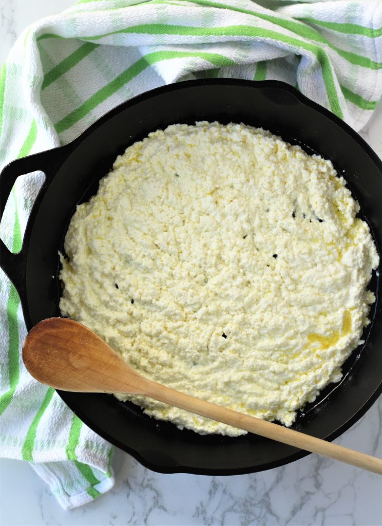 ricotta in cast iron skillet with wooden spoon