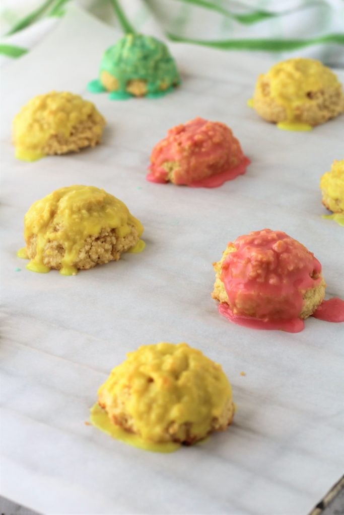colorful icing coated almond cookies dripping on parchment paper