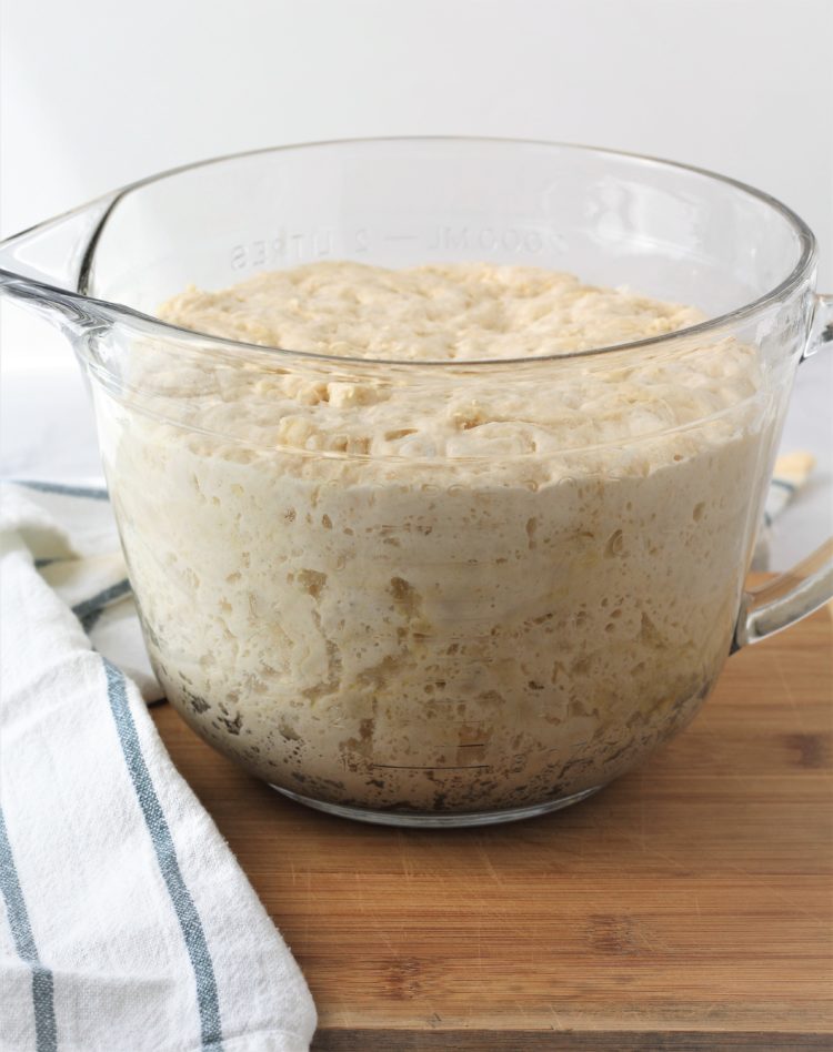 Bubbly no knead dough in large glass measuring cup.