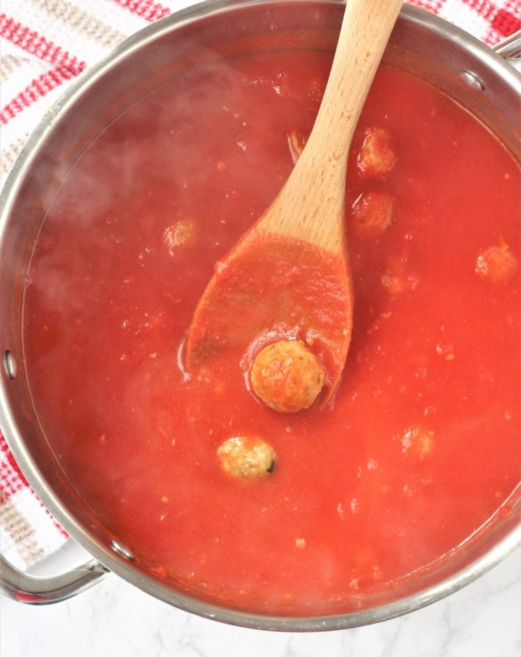 pot with tomato sauce and wooden spoon with meatball 